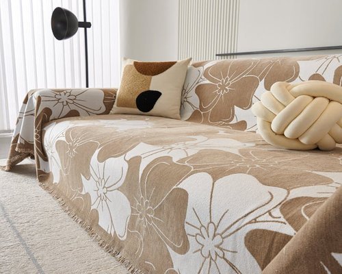 A person relaxing on a sofa with a warm, beige knitted blanket covering their legs